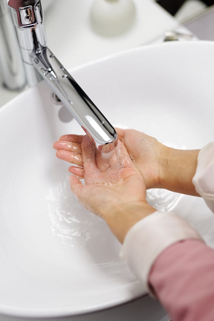 creative-02 Close-up of hands washing under running water in a modern sink emphasizing cleanliness and hygiene.